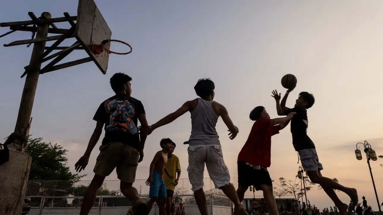 Alt Text: Community members playing Filipino Street Ball on an outdoor neighborhood court during sunset.