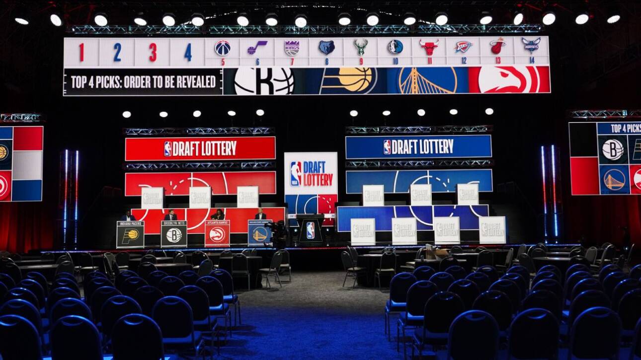 NBA Draft Lottery stage with large red and blue screens, team logos, and empty seating ahead of the event