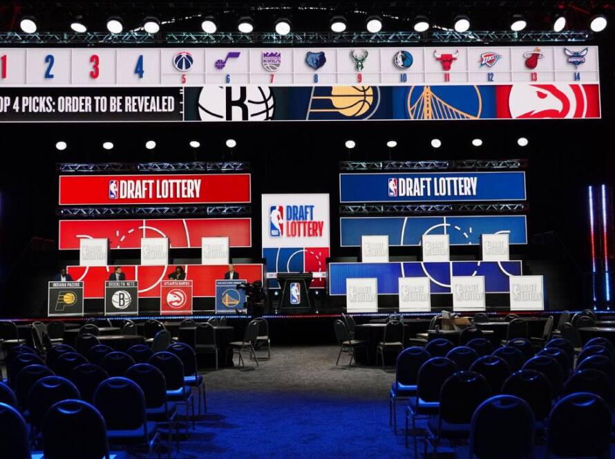 NBA Draft Lottery stage with large red and blue screens, team logos, and empty seating ahead of the event