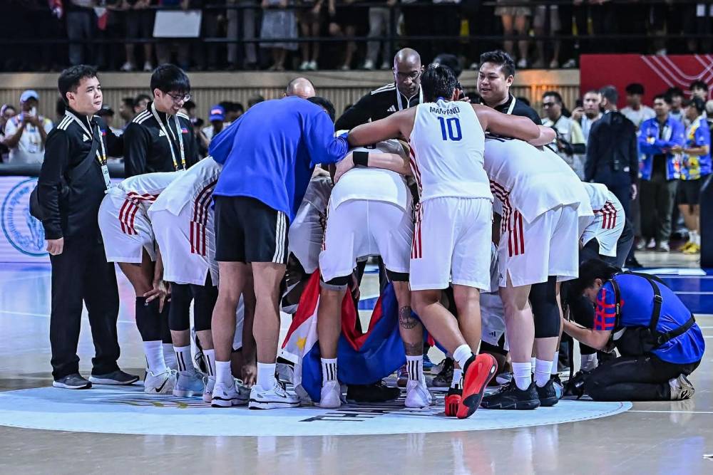 The Philippine men's national basketball team huddling during a timeout on the court.