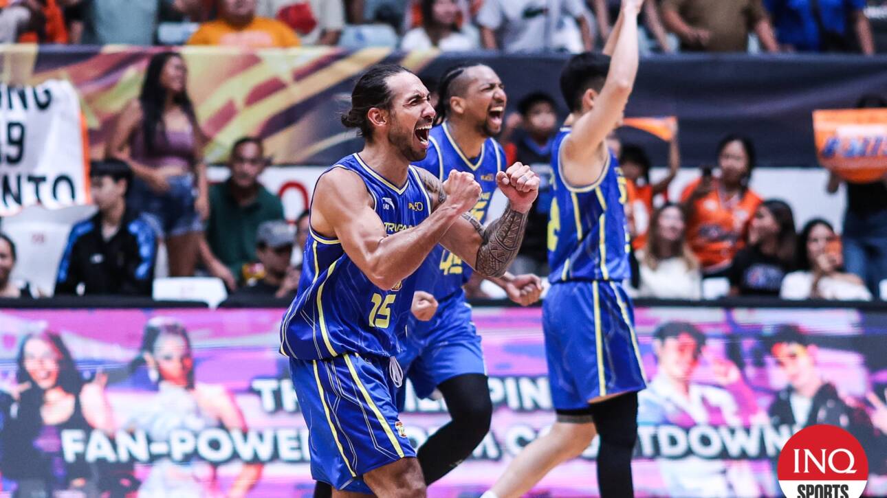 Basketball players in blue uniforms celebrate onscreen as the crowd cheers in the stands behind them.