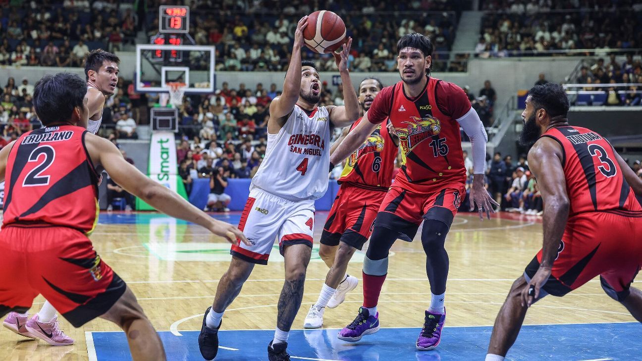 pba-all-defensive-team-rim-protection | GGSLOT | Sports & Games News An intense defensive play on a professional indoor basketball court, showing a defender leaping to contest a shot at the rim.
