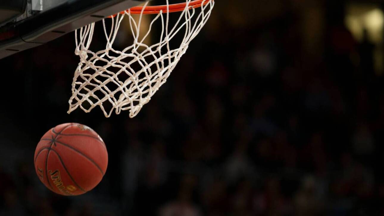 Basketball heading toward the hoop, about to go through the net during a game at the arena.