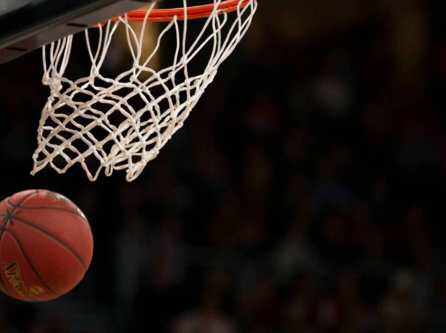 Basketball heading toward the hoop, about to go through the net during a game at the arena.